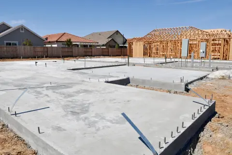 Fundament domu z chudego betonu, z widocznymi elementami konstrukcji drewnianej i instalacjami.