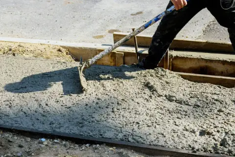 Pracownik rozprowadza świeży beton B25. Czas wiązania zależy od warunków, ale kluczowe jest odpowiednie przygotowanie.