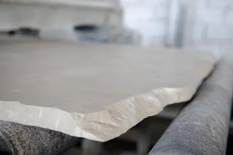 Surowy, jasny wapień na linii produkcyjnej. Kamień o nierównych krawędziach czeka na dalszą obróbkę.