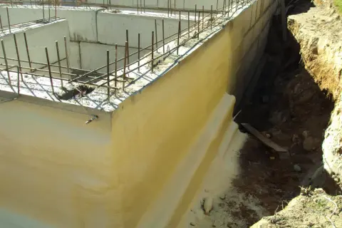 Izolacja fundamentów w starym domu w trakcie prac. Betonowe ściany zbrojone, gotowe do dalszych etapów budowy.