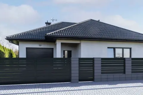 Nowoczesne ogrodzenie domu z ciemnoszarych paneli i betonowych słupków. Świetny pomysł na ogrodzenie domu, który podkreśla jego architekturę.