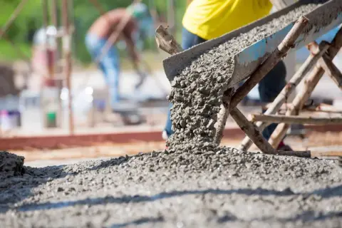 Beton wylewany z betoniarki. Pracownicy na budowie, którzy wiedzą, ile cementu na kubik betonu potrzeba do solidnej konstrukcji.