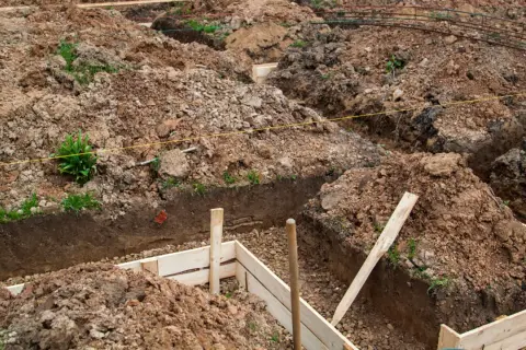 Wykonano wykopy pod fundamenty. Widać ziemię, drewniane szalunki i zbrojenie.
