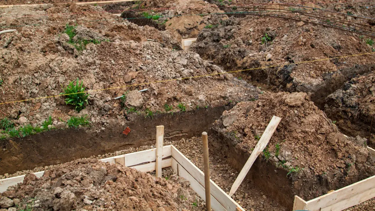 Wykonano wykopy pod fundamenty. Widać ziemię, drewniane szalunki i zbrojenie.